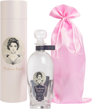 Das Foto zeigt die elegante Flasche des Madame Fagini Premium Dry Gins, stilvoll arrangiert mit einem dazugehörigen Geschenkbeutel sowie einer passenden Geschenkdose. Die Flasche besticht durch ihr hochwertiges Design, das klassische Eleganz mit modernen Details verbindet. Der Geschenkbeutel verleiht dem Set einen luxuriösen Touch, während die Dose das Gesamtbild abrundet und gleichzeitig Schutz sowie Stil bietet – ideal als exklusives Präsent oder für die stilvolle Aufbewahrung.