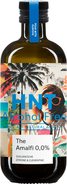 Auf dem Bild ist eine braune Glasflasche mit schwarzem Schraubverschluss und blauem Halsbandetikett zu sehen, auf der ein buntes, collageartiges Etikett mit Palmen, Meer- und Strandmotiven sowie einem Frauenporträt dominiert. Auf dem vorderen, weißen Feld des Etiketts steht „The Amalfi 0,0%“ und darunter die Geschmacksbeschreibung „Sizilianische Zitrone & Clementine“