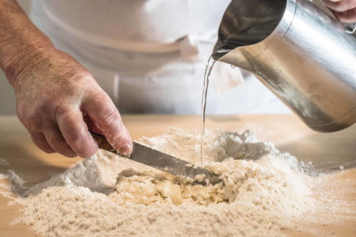1. Teig ansetzen: 200 g Mehl kegelförmig auf dem Nudelbrett aufhäufen, oben einen Krater bilden. Öl, eine Prise Salz und nach und nach 1/8 l Wasser zugeben und mithilfe eines breiten Messers oder einer Spachtel vermengen – gut möglich, dass Sie nicht alles Wasser brauchen.