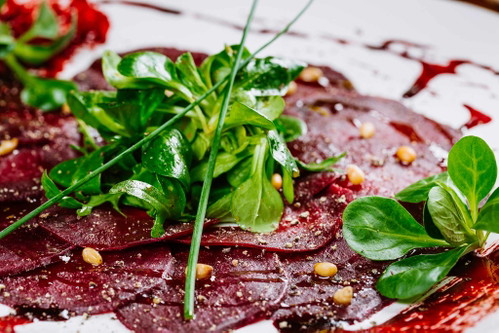CARPACCIO (ITALIEN): In Venedig erfunden, hat sich das Carpaccio schnell verbreitet. Es besteht aus hauchdünn geschnittenem Fleisch, das mit einer Vinaigrette mariniert und kühl serviert wird. Mittlerweile ist das Gericht so beliebt, dass es bereits vegetarische und vegane Versionen davon gibt. Der Kreativität ist beim Anrichten keine Grenze gesetzt, es passen zum Beispiel Parmesan, Pinienkerne und Vogerlsalat ausgezeichnet zum Carpaccio.