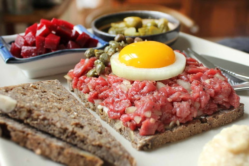 TARTARMAD (DÄNEMARK): Was des Italieners Pasta, ist des Dänen «Smørrebrød». Das dick belegte Brot wird mit Messer und Gabel gegessen und mit Aufstrichen oder Aufschnitt garniert. So auch mit Tartarmad, das aus frischem, rohen Rindfleisch besteht und mit Zwiebeln, Salz und Pfeffer vermengt wird. Dazu werden Kren und Essiggurken gereicht. Der Dotter in der Mitte rundet den Geschmack ab.