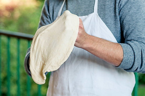 Zwei Stunden vor dem Backen portionierenNehmen Sie den Teig zwei Stunden vor dem Backen aus dem Kühlschrank und portionieren Sie ihn. ­Direkt vor dem Backen wird er geformt: rund ausrollen und dann auf den Fingerknöcheln hängend kreisen lassen, bis er die richtige Größe hat.
