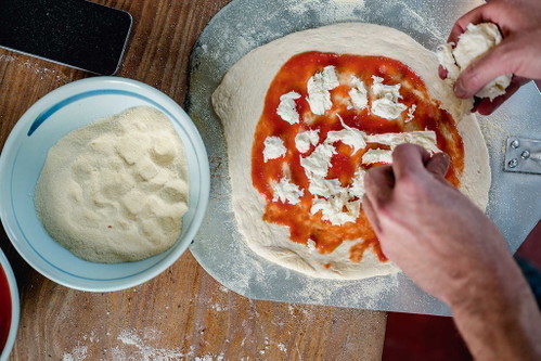 Lieber erst auf der Schaufel belegenBelegen Sie Ihre Pizza am besten erst, nachdem Sie den Teig bereits auf die Pizzaschaufel transferiert haben – das verhindert, dass der Teig reißt. Hartweizengrieß auf der Arbeitsfläche macht das Pizzaiolo-Leben ebenfalls leichter. 