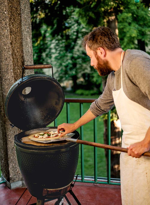 Mit ruhiger Hand und einer ruckartigen Bewegung wird die Pizza von der Schaufel auf den Grill befördert. Das Big Green Egg ist ideal geeignet, kleinere Kugelgriller tun’s aber mit guter Kohle auch.