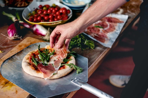 Nur mit Tomatensauce und Käse gebacken und dann heiß aus dem Ofen mit Rucola und Prosciutto belegt: Pizza mit Rohschinken kommt ­immer gut an.