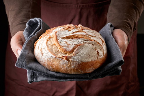Frisch gebackenes Brot in Bäckerhänden.