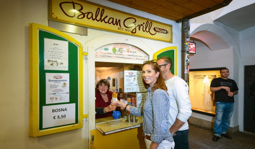 »Geburtsort« der Bosna: Der »Balkan-Grill« in einem Durch-haus in Salzburg (o.). Beim Wiener Würstelstand werden zur Bosna Rohscheiben serviert – so sagte man früher in Wien zu Kartoffelchips –&nbsp;gerne mit Pinzgauer Schottkas »aufgepeppt«.