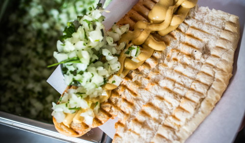 1. Das extra für die Bosna hergestellte Bio-Weckerl von der Bäckerei Gragger wird aufgeschnitten und am Panini-Grill getoastet. Auf Estragonsenf wird dann eine frische Zwiebel-Petersil-Mischung üppig verteilt.