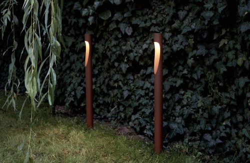 Das Leuchtmittel der schlanken Pollerleuchte »Flint Garden« von Louis Poulsen sitzt im oberen Teil der asymmetrischen Öffnung. Diese lenkt das Licht weich und organisch in Richtung Boden.