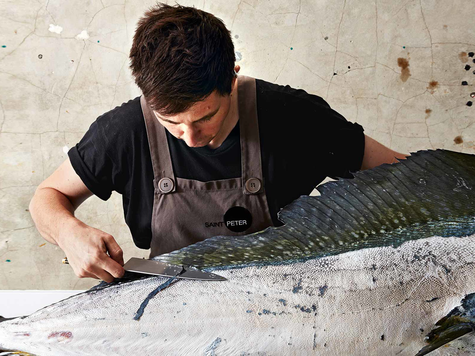 Mit einem extrem scharfen ­Messer schneidet Niland einem Mahi Mahi die Schuppen in ­langen Bändern vom Leib. Sie werden später zu Chips frittiert.