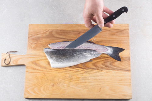 Das erste Filet von der Rückenseite her und entlang der Rückengräten vom Körper trennen. Dabei in kleinen, kontrolliert gesetzen Schnitten agieren und mit den Fingern nachfühlen, um möglichst nah an der Gräte zu schneiden.