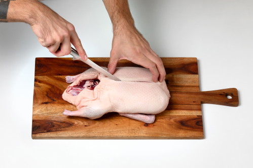 Der erste Schnitt Legen Sie den Vogel mit der Brust nach oben auf ein Brett, am besten so, dass die Bauchöffnung zu Ihnen zeigt. Entfernen Sie die Innereien und etwaiges überschüssiges Fett aus dem Bauchraum und beginnen Sie dann, zuerst die Brüste auszulösen.