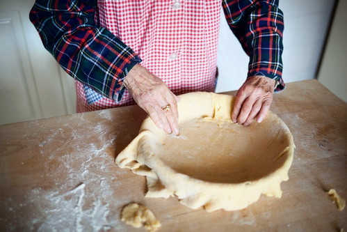 4. Pastiera zusammenbauen
Den überhängenden Teigrand abschneiden und die Teigreste aufheben – sie werden noch für die Dekoration gebraucht. Die Füllung in die Form geben und mit einem Löffel gleichmäßig darin verteilen.