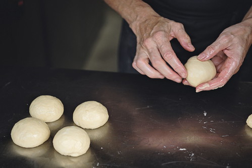 7. Knödel schleifen Die Teigstücke mit angefeuchteten Handflächen zu glatten, runden Knödeln schleifen.