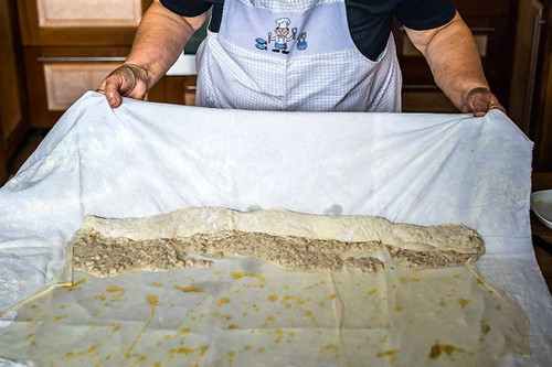 8. Strudel rollen. Den Strudel mit dem Tuch nach und nach rollen. Keine Angst vor kleinen Löchern mit austretender Masse – das passiert auch den Profis und ändert nichts am Geschmack.