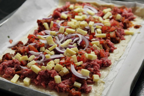 Pizzateig mit Zutaten belegen.
