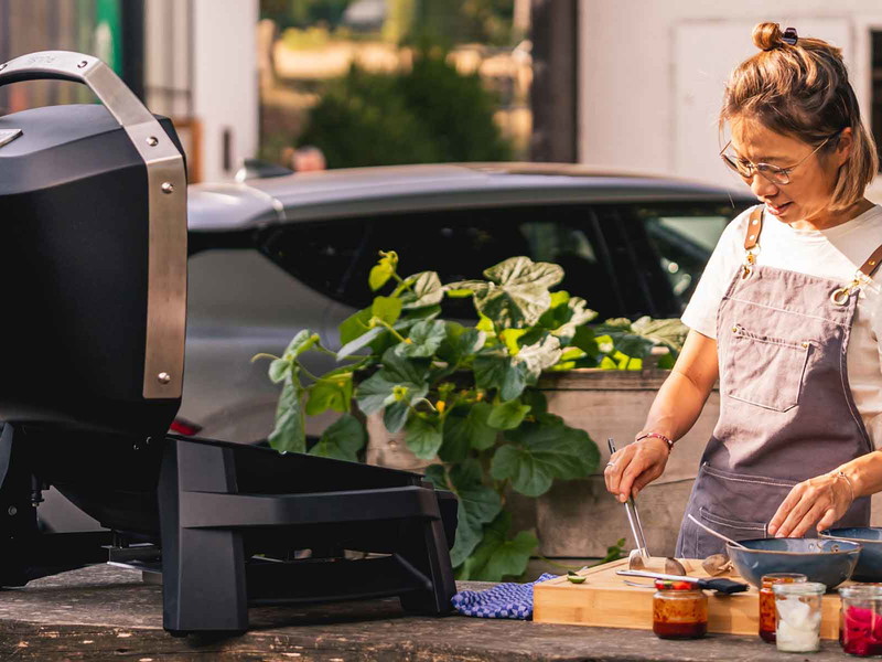 Sarah Henke beim Open-Air-Kochen mithilfe eines Grills, der seinen Strom aus dem Elektrofahrzeug »Kia EV6*« bezieht.