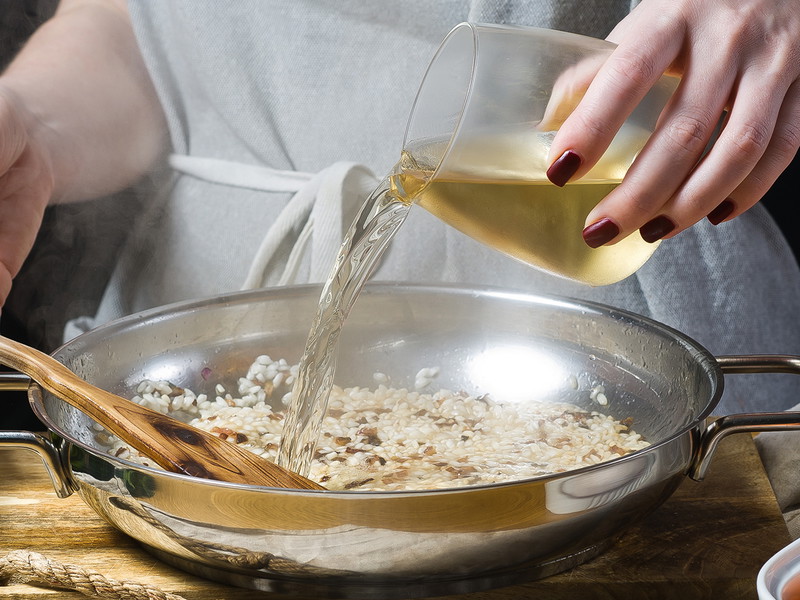 Risotto wird erst mit Wein abgelöscht und dann mit heißer Brühe aufgegossen. Das Ergebnis muss cremig sein, die Körner bissfest.