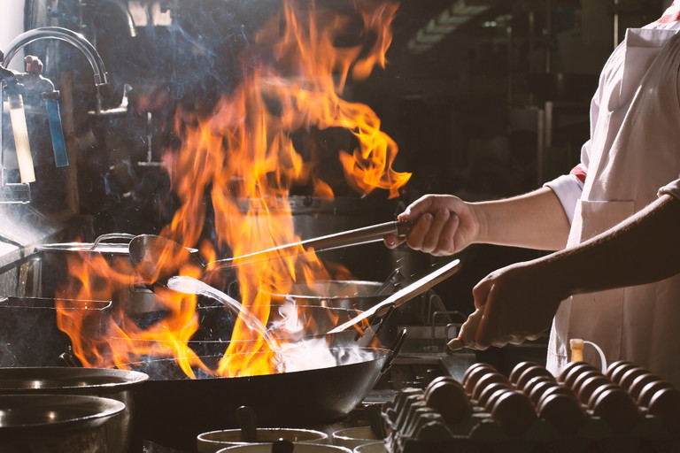 Chef stir fry busy cooking in kitchen. Chef stir fry the food in a frying pan, smoke and splatter the sauce in the kitchen.