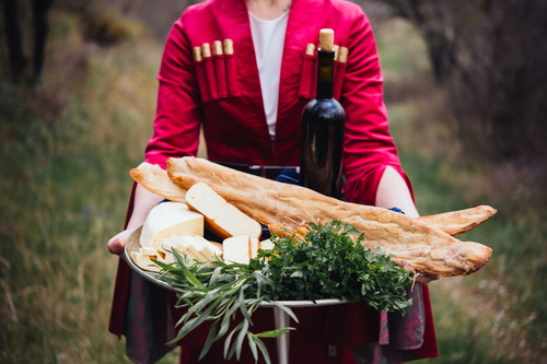 A tray full of traditional Georgian food: cheese, bread, greens and wine.