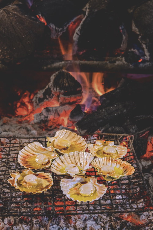 Jakobsmuscheln. 
Die Zubereitung über dem Feuer verleiht den Muscheln ein leicht rauchiges Aroma und macht das Fleisch ganz zart.