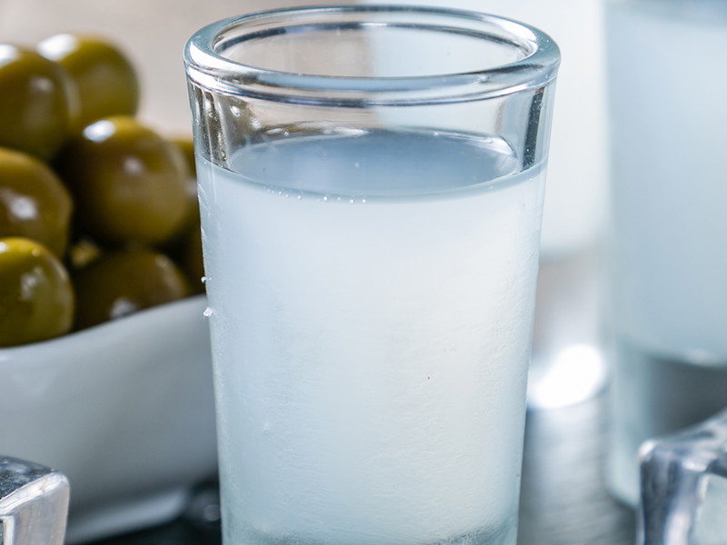 Traditional greek vodka - ouzo in shot glasses on rustic wood background