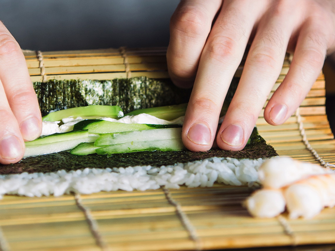 Rolling up sushi on a bamboo mat.