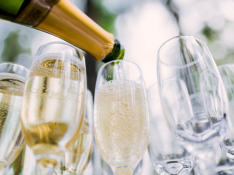 the waiter pours champagne in glasses on the street - wedding catering - look from below