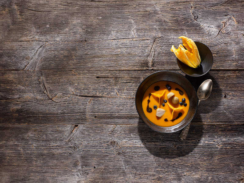 Kürbissuppe mit eingelegten Heidel- und Erdbeeren, Kürbiskernöl sowie eingelegten Kürbisblättern