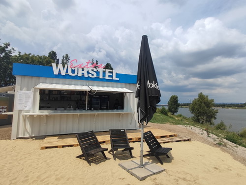 Der Imbiss »Extra Würstel« mit Sandstrand und Ausblick