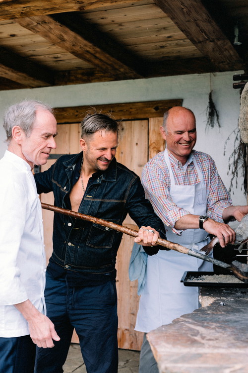 On fire. Karl und Rudi Obauer mit Philipp Hochmair in Aktion beim Grillen am offenen Feuer. Spaß inklusive.