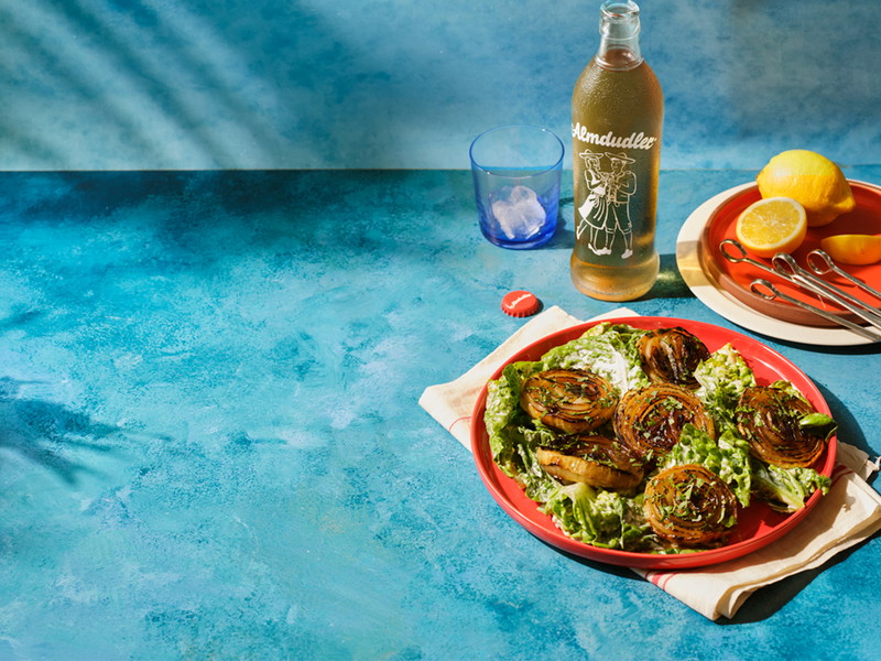 Gegrillte Zwiebelsteaks mit Almdudler-Senf-Marinade auf veganem Caesar-Salat