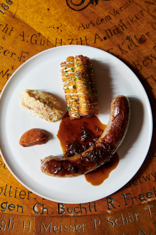 Die Züri Wildbratwurst mit Trüffel-Röstikroketten, karamellisierter Zwiebelsauce und Speck-Champagnerkraut.
