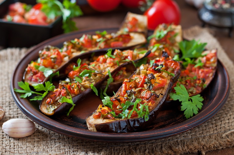Gebackene Auberginen belegt mit Mix aus Tomaten, Knoblauch, Paprika und Peterli.