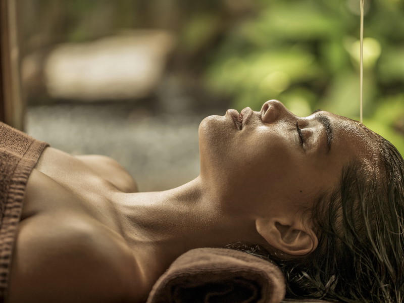 Ayurvedischer Stirnguss. Die Shirodhara-Behandlung mit warmen Öl ist eine bewährte Methode, um dem Gedankentunnel zu entkommen.