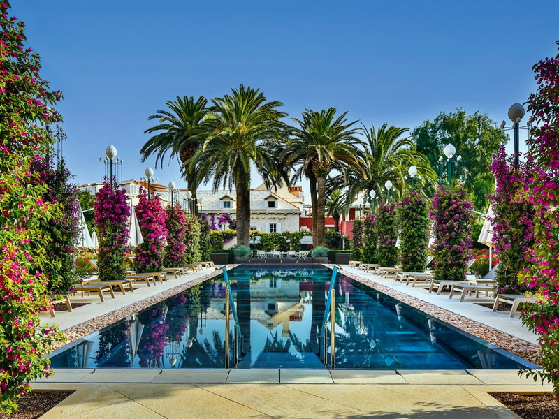 Der Pool des »Hotel Lemongarden« leuchtet blau zwischen Palmen, Zitronenbäumen und Blütenpracht.