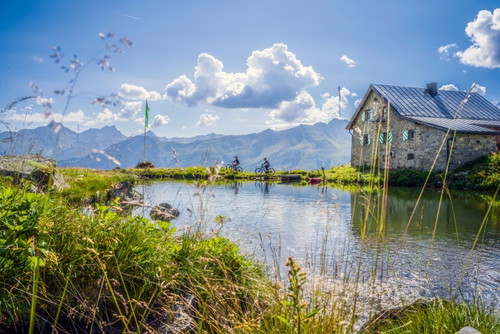 Bergsee mit Hütte oder Hotel am Strand? Die alpine Landschaft über Ischgl erleichtert Mountainbikern die Antwort.