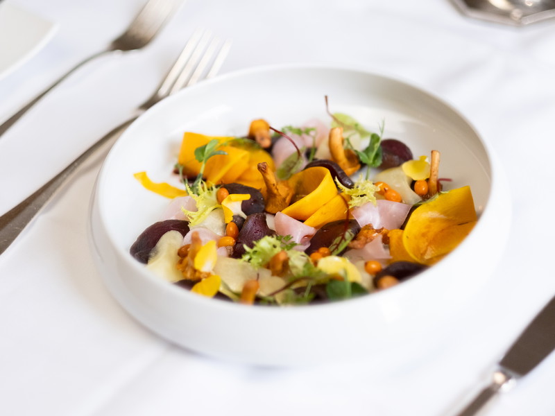 Carpaccio vom Muskat Kürbis mit Cassis, karamellisierten Kürbiskernen, Vogelbeeren und Federkohlcrunch.