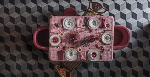 Piatti da frutta e servizio decorati con fiori, poi bicchieri, calici e bottiglia coordinati, una tovaglia dall’effetto sfumato e i segnaposto decorati.