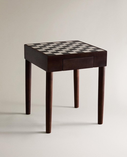 Il tavolino ausiliario in teak ha un ripiano superiore con effetto scacchi in marmo e un pratico cassettino per riporre gli scacchi a fine partita.