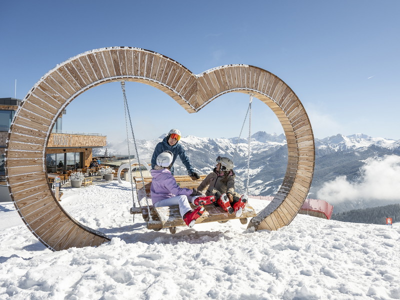 Skigenuss mit Freunden bei der herzförmigen Schaukel oberhalb des Bergrestaurants Wolke 7.