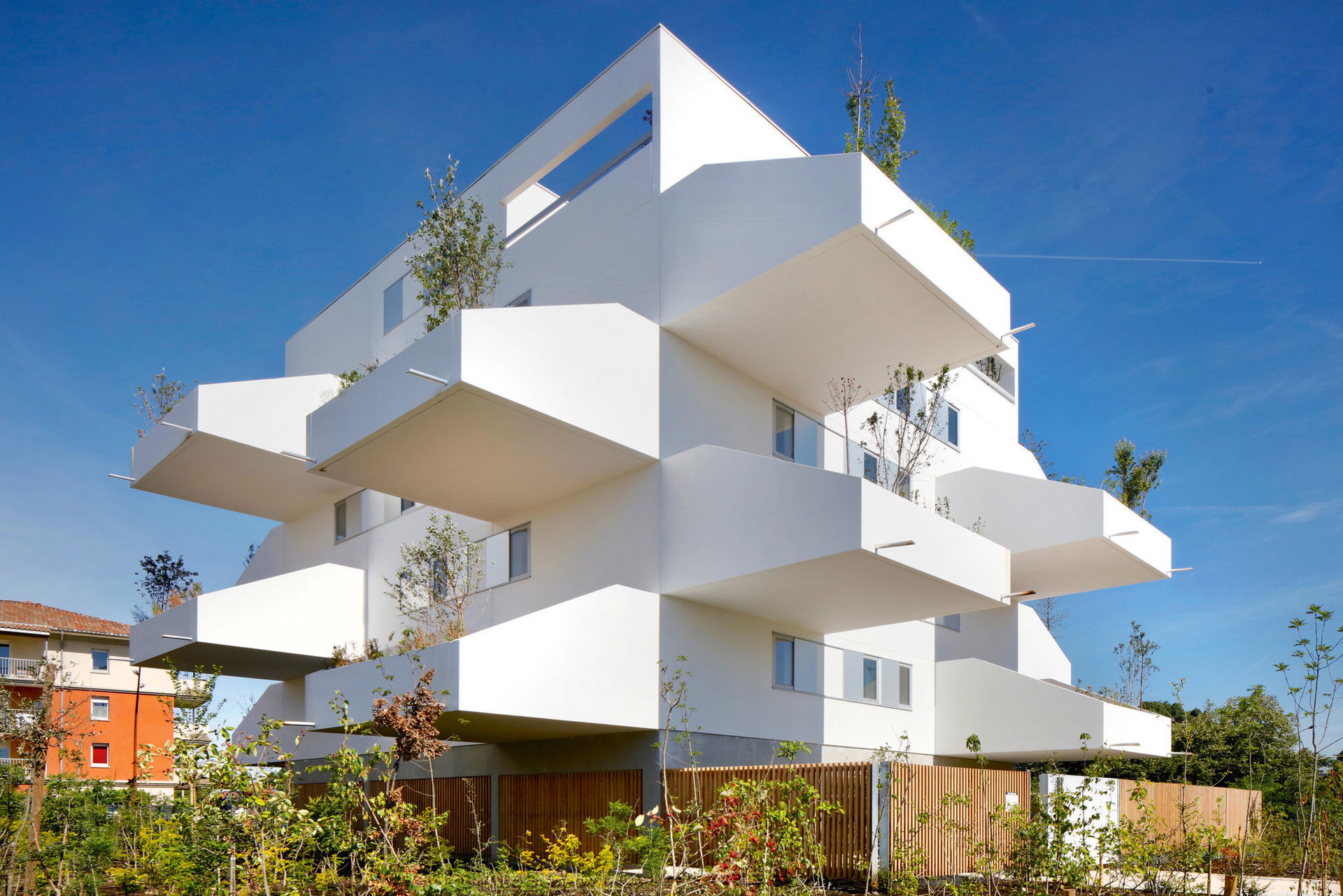 Square Maimet, Muret (FR):&nbsp;Einen Hauch von Ferienapartment-Komplex in einem luxuriösen Küsten-Resort strahlt diese Anlage in Muret bei Toulouse aus. Strahlend weiße Stadt-villen mit auffällig weit auskragenden Balkonen: Für die Architekten stand hier die Idee von vertikal gestapelten Häusern mit Gärten Pate. Eingebaute Pflanztröge bieten Platz für größere Bäume und viel Grün. Das Erstaunliche: Es handelt sich hier nicht um Luxus-Apartments, sondern um Sozial-wohnungen. Glückliches Frankreich! ppa-a.fr