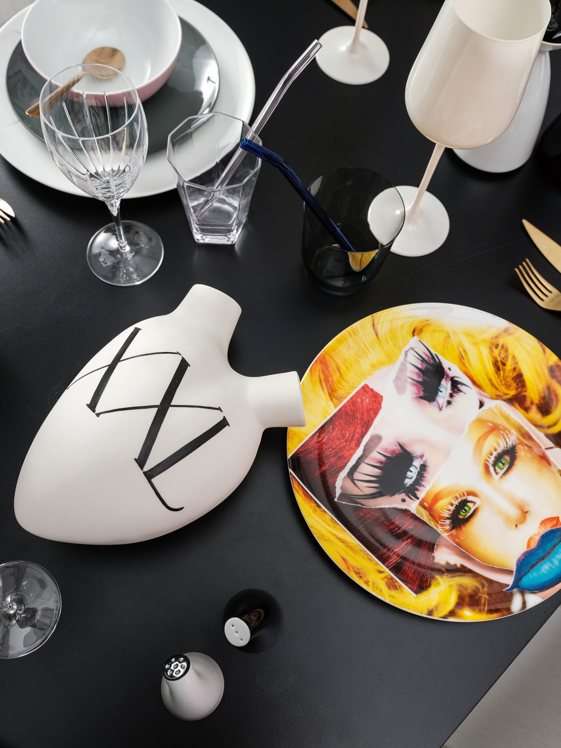 Herzvase XXL von Fos via Ma Maison. ma-maison.at; Teller mit Dragqueen von Martin Schoeller für Rosenthal via Cuisinarum. cuisinarum.at; Tumbler aus dunklem Glas und Besteck von Mepra, beides via Feine Dinge. feinedinge.at; Glastrinkhalme und weißes Weinglas, beides von Zara Home. zarahome.com; Weinglas »Iriana« von Christofle via Cuisinarum. cuisinarum.at; Wasserglas von Lobmeyr. lobmeyr.at
