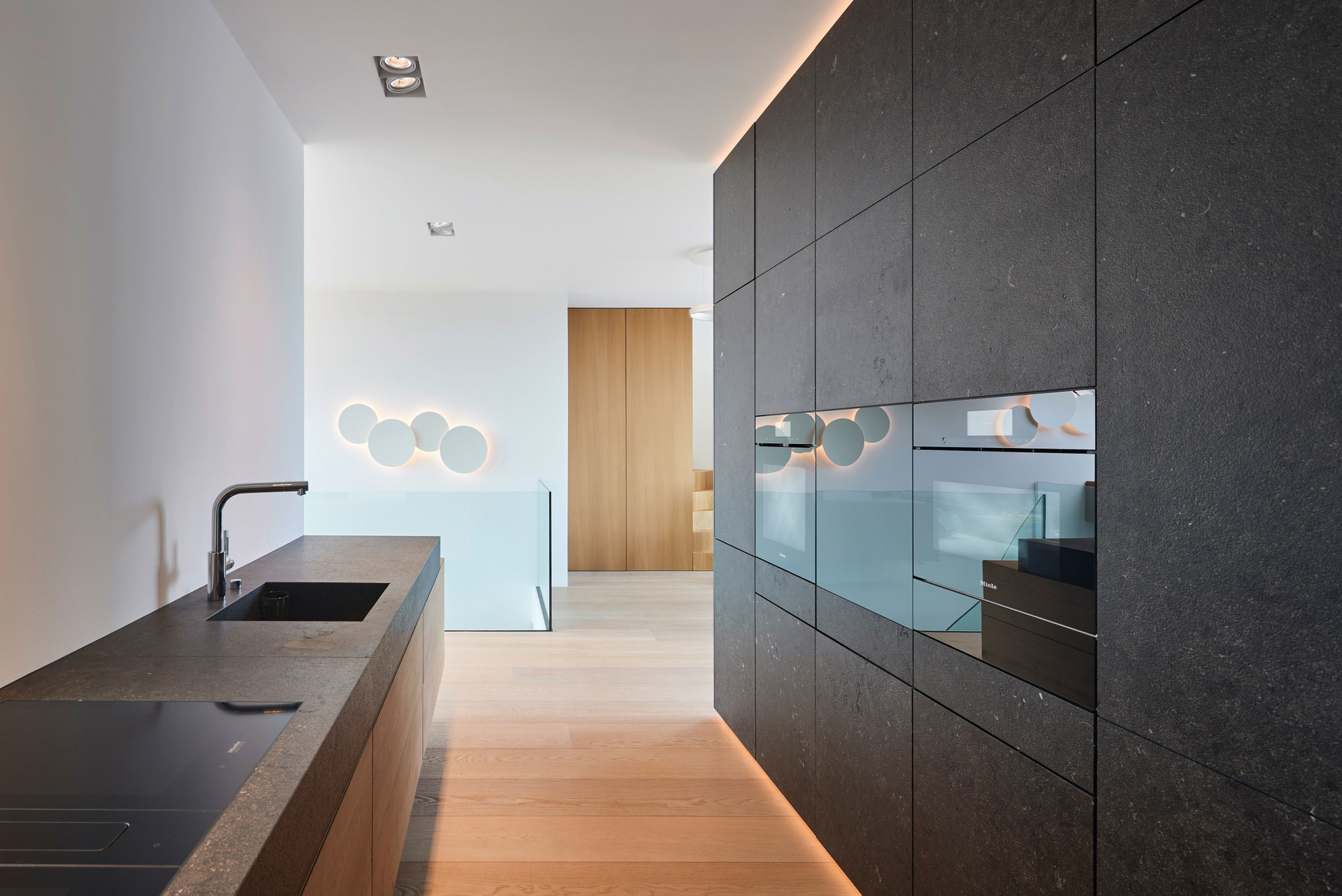Das »Penthouse H.« in Wien wurde von Steinkogler Aigner Architekten geplant und mit belgischem Kalkstein von Breitwieser ausgestattet. Raffiniert: Hier gibt es nicht nur eine Küchenzeile, hinter der Stein­fassade (rechts im Bild) befindet sich ein monolithischer Raum im Raum, der Platz für eine Speis bietet. breitwieser.design, steinkogleraigner.at