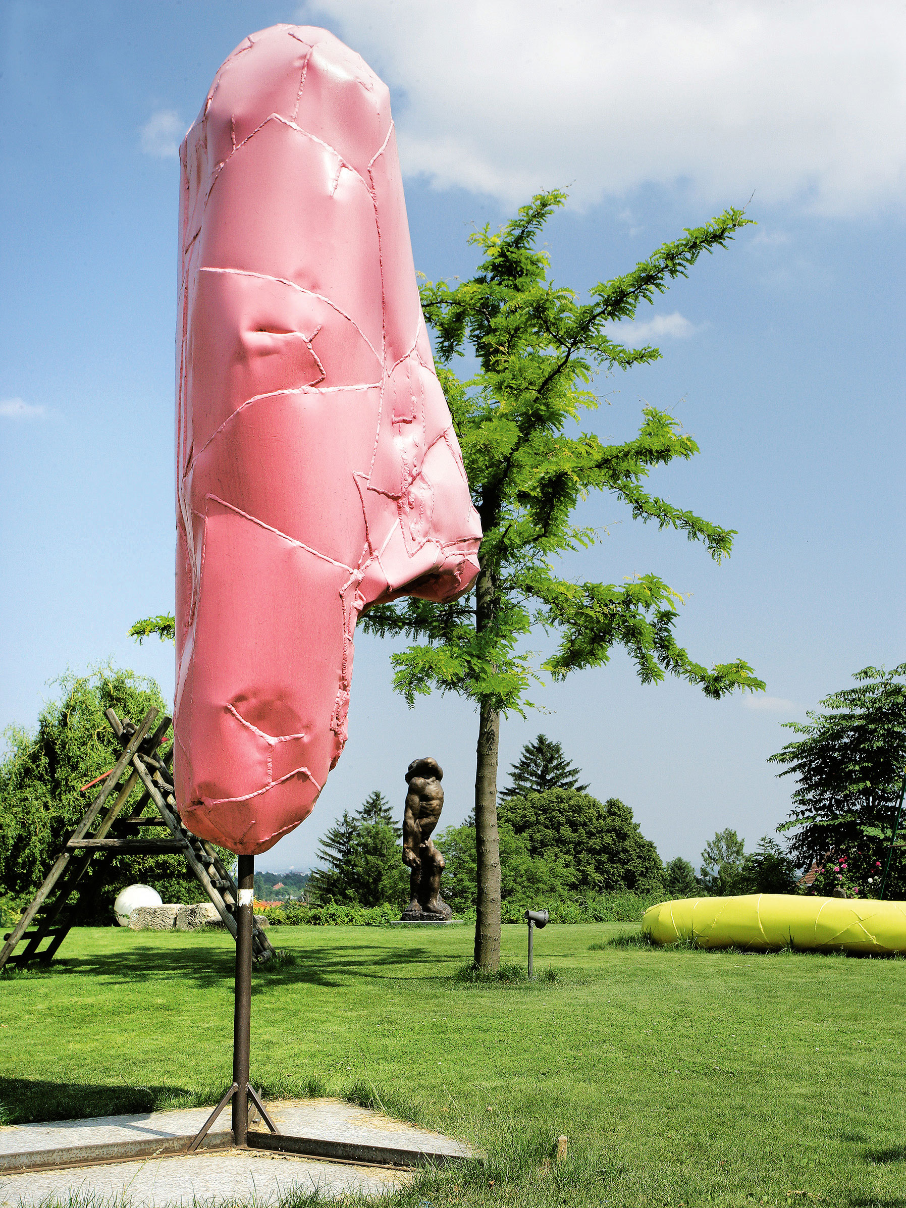 Skulpturengarten: Grüne Blickachsen für die Kunst: ein Lemuren-Kopf von Franz West, dahinter eine Skulptur von Alfred Hrdlicka im Garten von Roman und Margot Fuchs.