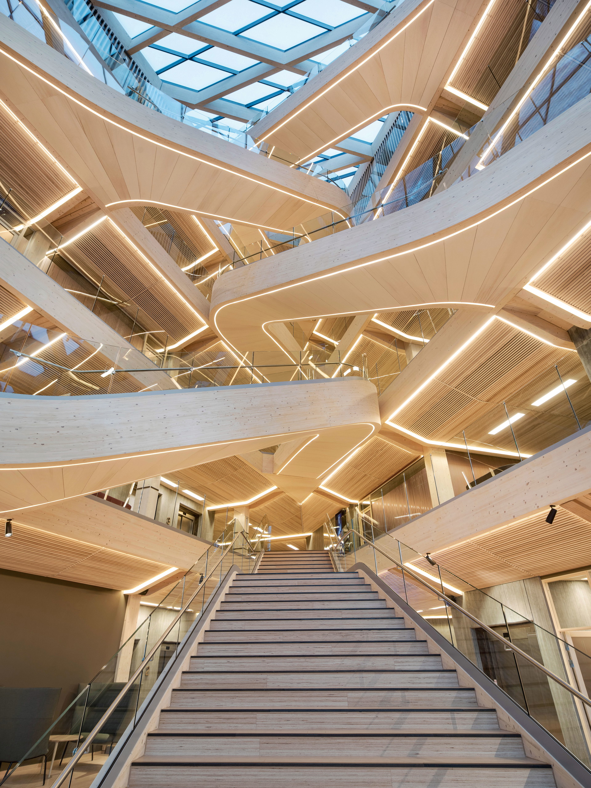 SR-Bank in Stavanger, Norwegen: Wie schafft man Wohlbefinden für Hunderte Mitarbeiter in einer der größten Banken Norwegens? Die beiden Architekturbüros SAAHA und Helen &amp; Hard fanden die Antwort darauf im nachwachsenden Rohstoff Holz. Das Material sorgt nicht nur für Ruhe, Stressresistenz und bauphysikalische Behaglichkeit, sondern liefert auch einen Weltrekord: Mit 19 Meter Länge handelt es sich bei den Treppenläufen im sechsgeschoßigen Foyer um die größten frei- tragenden Holztreppen der Welt. helenhard.no, saaha.no