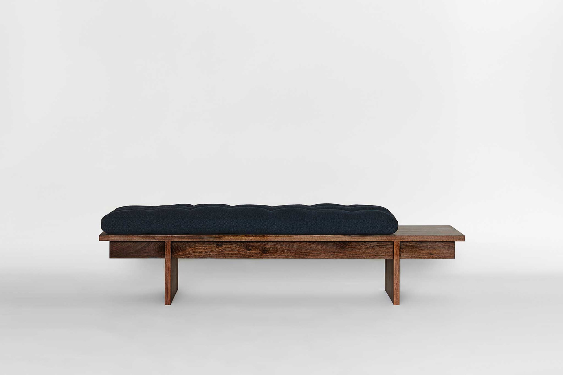 Mit seinem geradlinigen Holzrahmen in&nbsp;Eiche massiv oder Nussbaum hat das Daybed aus der Kollektion für Mjölk eine reduzierte, archetypische Form.&nbsp;Die daunengefüllte Matratze verleiht dem Design Weichheit.