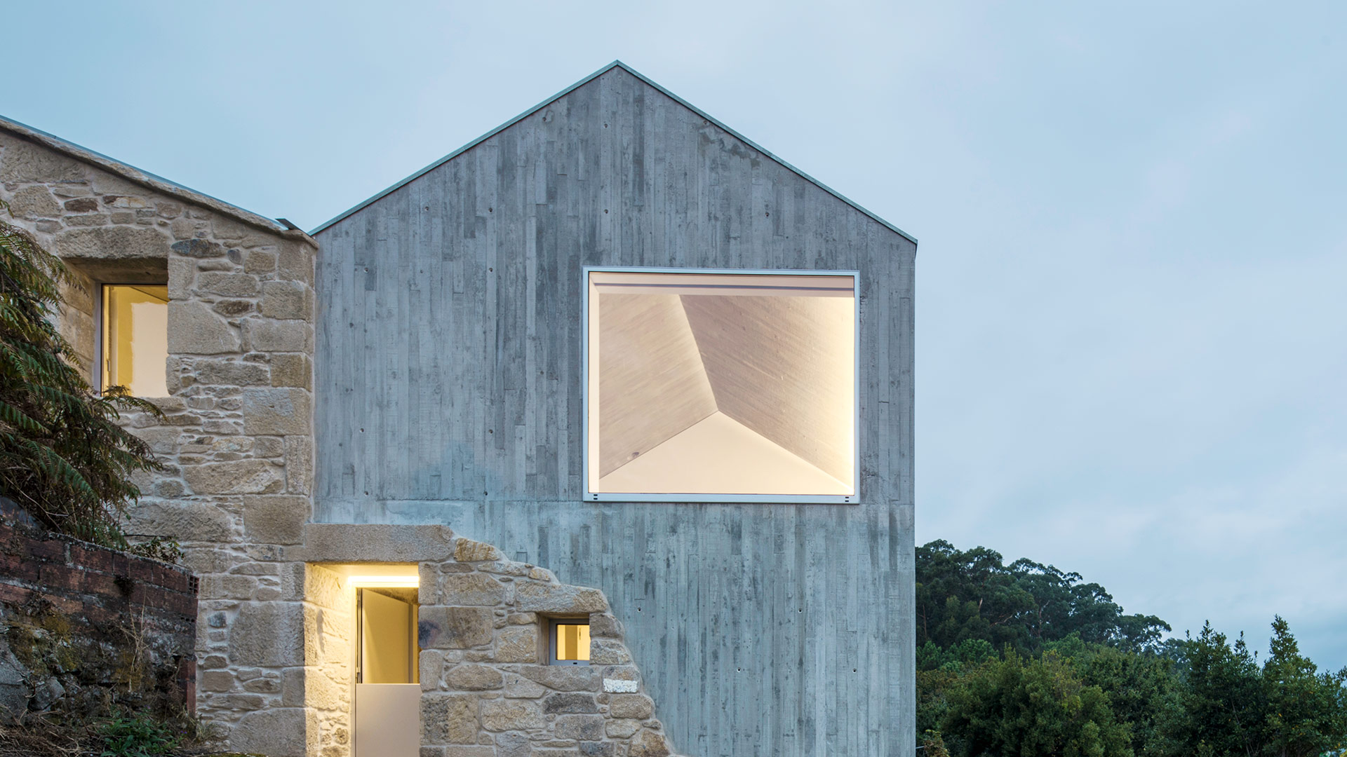 Muros ist ein kleines Küstendorf in der Nähe von Santiago de Compostela. Die Region ist landwirtschaftlich geprägt, die alten Holz- und Steinhäuser bis heute Teil der lokalen Identität. Fuertes-Penedo Arquitectos orientierten sich an dieser Tradition und wählten für den Zubau des alten Steinhauses eine Neuinterpretation des mineralischen Baustoffs – in flüssiger, monolithischer Form unter Zusatz von Zement. Alt und Neu gehen auf diese Weise eine zwar brutalistische, aber konkurrenzlos schöne Symbiose ein. fuertespenedo.com