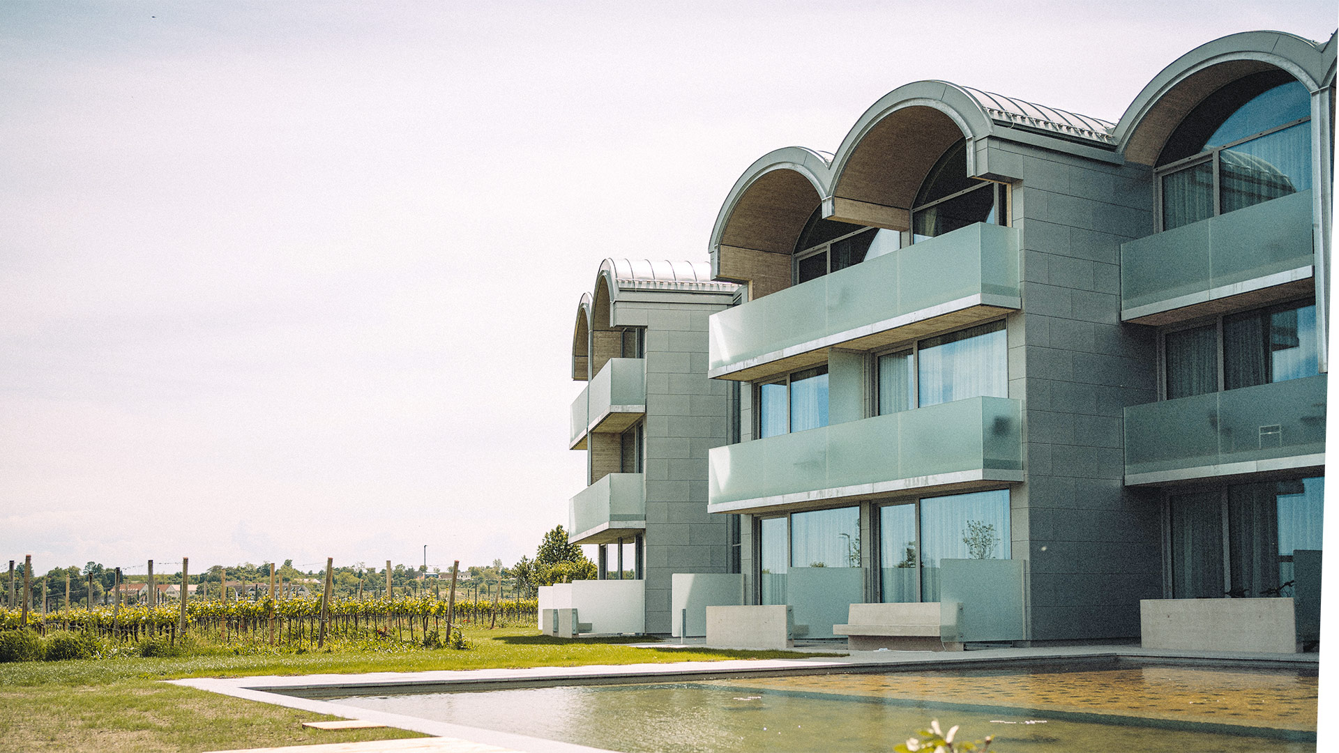 Gemeinsam mit dem New Yorker Architekten Steven Holl plante Franz Sam den Erweiterungsbau zum bestehenden »Loisium«-Hotel in Langenlois. Der Sichtbeton prägt nicht nur das äußere Erscheinungsbild, sondern schlägt sich auch in den Innen-räumen nieder. In der Oberfläche ist die Holzstruktur der groben, sägerauen Schalungsbretter gut zu erkennen. Seit dem Frühjahr sind die 30&nbsp;neuen Zimmer in Betrieb, sieben davon sind von -einem fünf Meter hohen Tonnengewölbe gekrönt. stevenholl.com, sam-architects.at, loisium.com