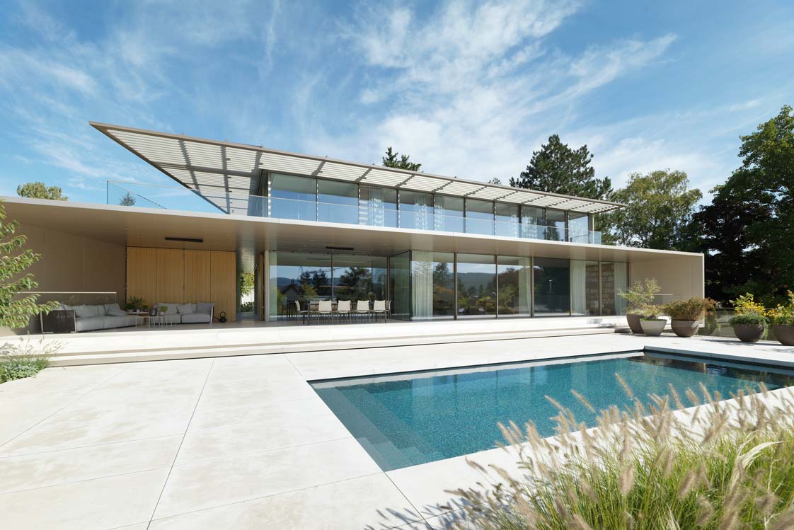 365 Tage Urlaubsfeeling&nbsp;Viel Glas, spanischer Sandstein und ein Outdoor-Pool. Dominik Aichinger schuf ein Haus, das sich materiell zurücknimmt, dafür aber die umliegende Natur regelrecht in den Innenraum hineinsaugt.&nbsp;aichinger.at